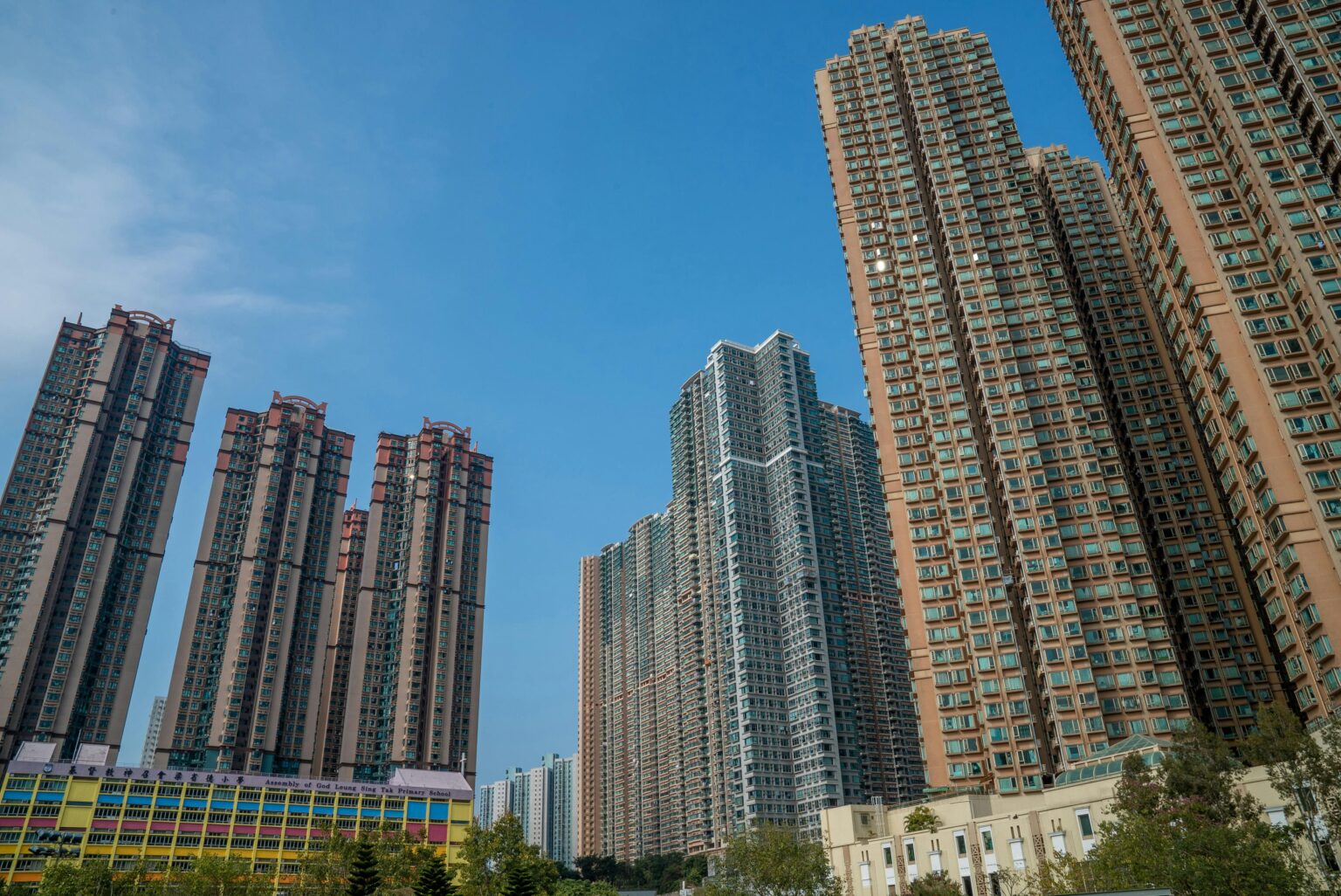 High-rise buildings in Hong Kong under a clear blue sky, showcasing urban density and modern architecture.